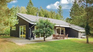 Une maison moderne dotée d’un grand patio, d’un coin repas et d’un garage.