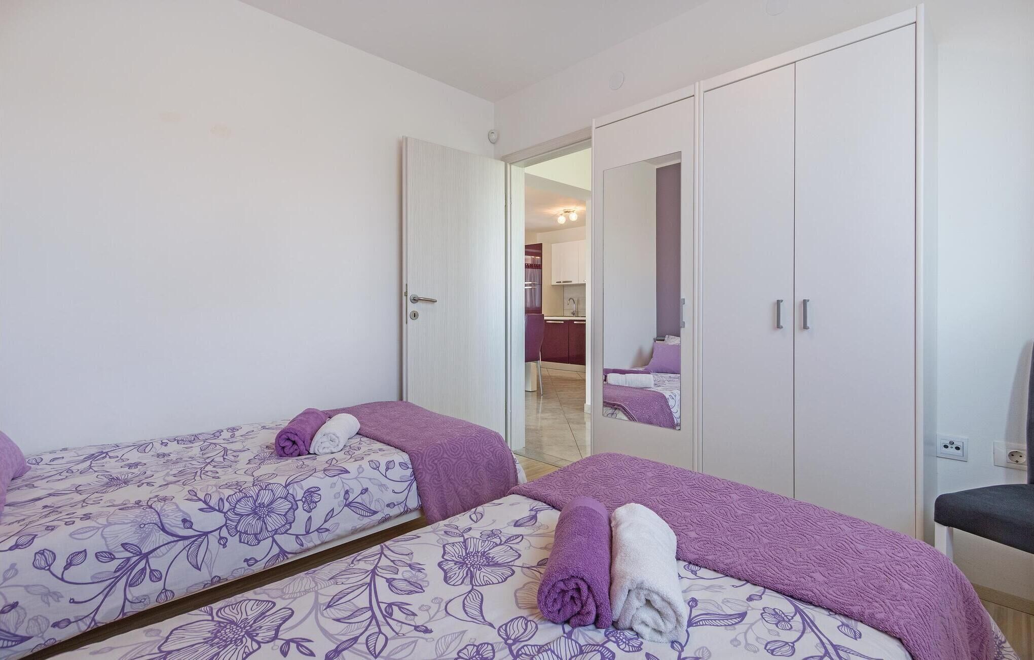 A bedroom with two beds, a wardrobe, and a mirror.