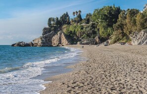 A beach with rocky cliffs and palm trees. - Gorgeous apartment in Nerja (Nerja)