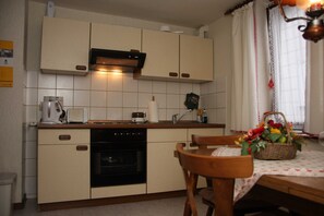 Une cuisine équipée d’une cuisinière, d’un four et d’une table à manger avec des chaises.