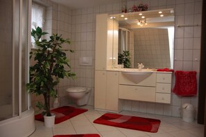 A bathroom with a toilet, sink, mirror, and a potted plant.