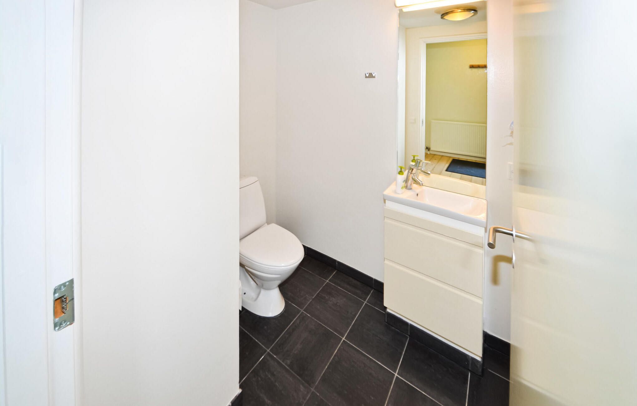 A small, clean bathroom with a toilet, sink, and mirror.