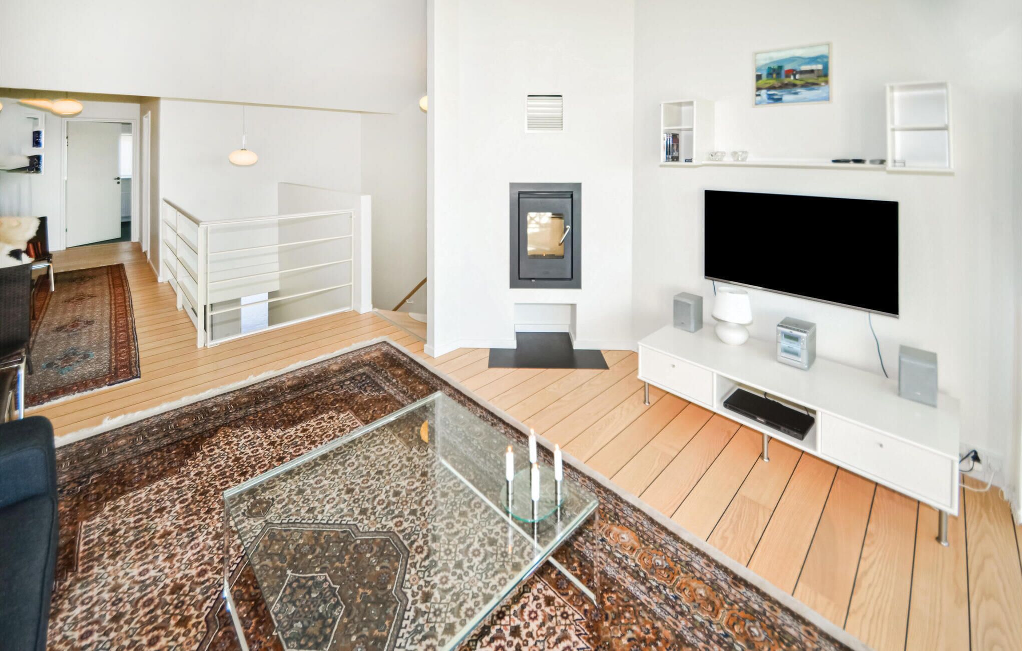 Un salon moderne doté d’un grand téléviseur à écran plat, d’une table basse en verre et d’un tapis à motifs.
