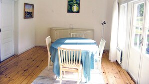 Et spiseområde med et bord dækket til fire personer, en radiator og et vindue med gardiner.