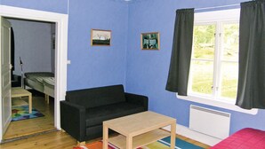 Et værelse med en sort sofa, et lille træbord og et vindue med gardiner.