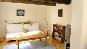 En hyggelig stue med en hvid sofa, et træbord, en reol og et fjernsyn.