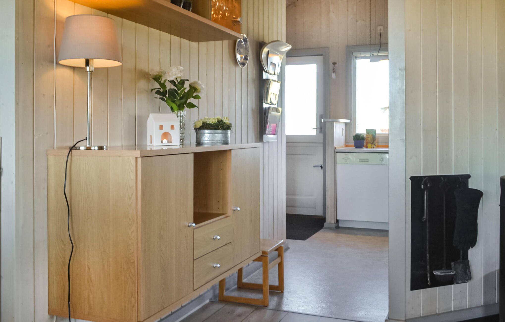 Une cuisine avec des meubles de rangement en bois, un petit tabouret, un évier et une cuisinière.