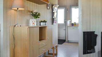 Une cuisine avec des meubles de rangement en bois, un petit tabouret, un évier et une cuisinière.