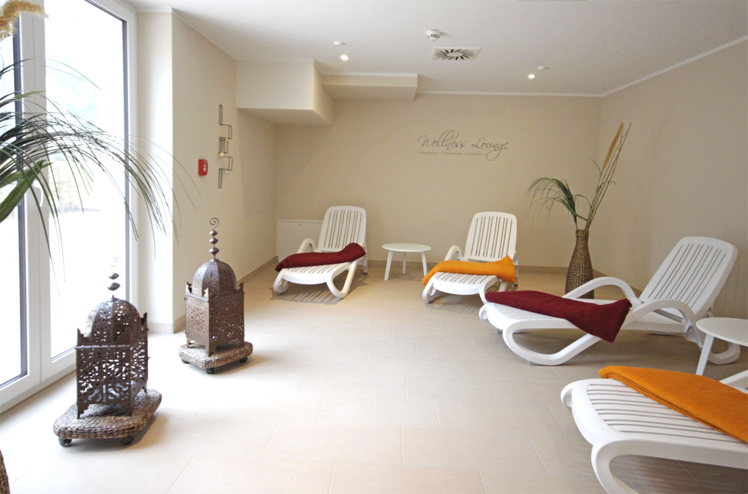 Een spa-ruimte met witte loungestoelen, een klein tafeltje en decoratieve metalen lantaarns.