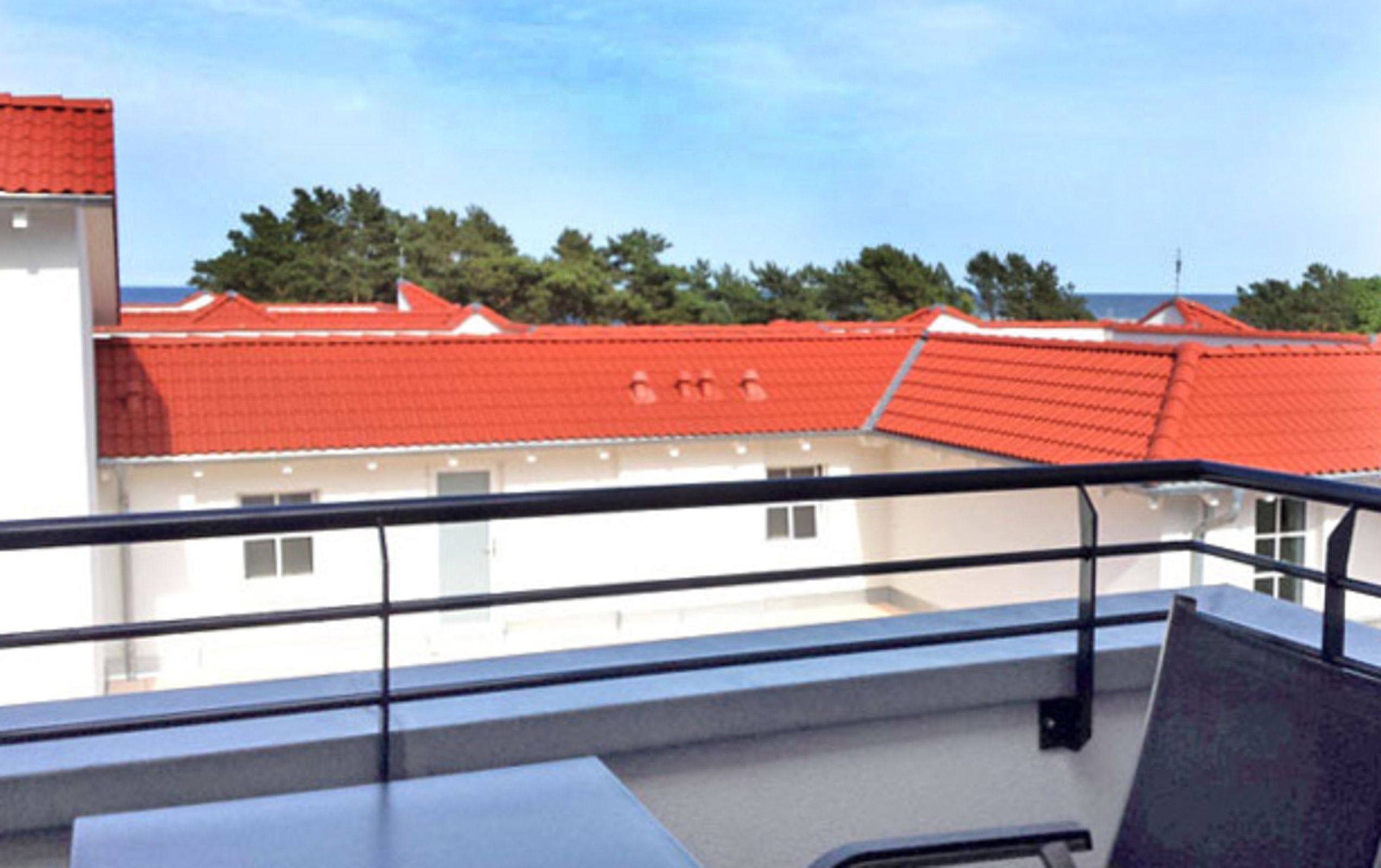 Ein Balkon mit Blick auf Gebäude mit roten Dächern.