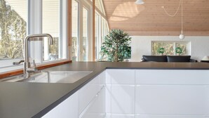 A modern kitchen with a stainless steel sink, white cabinets, and a wooden ceiling. - Cozy home in ålbæk with sauna (Ålbæk)