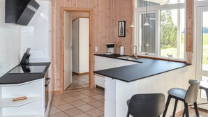 A modern kitchen with a black countertop, white cabinets, and a window with a view of greenery. - Cozy home in ålbæk with sauna (Ålbæk)