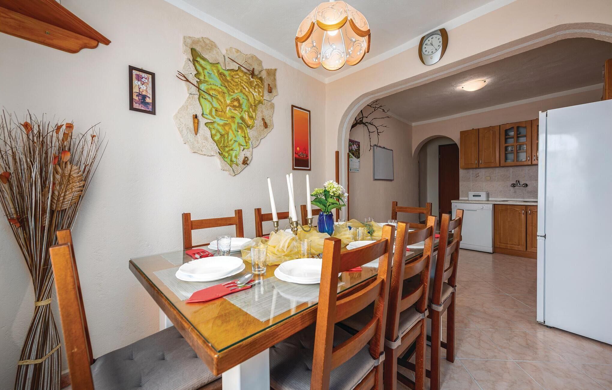Un coin repas avec une table en bois dressée pour quatre personnes, un vase rempli de fleurs et une carte accrochée au mur.