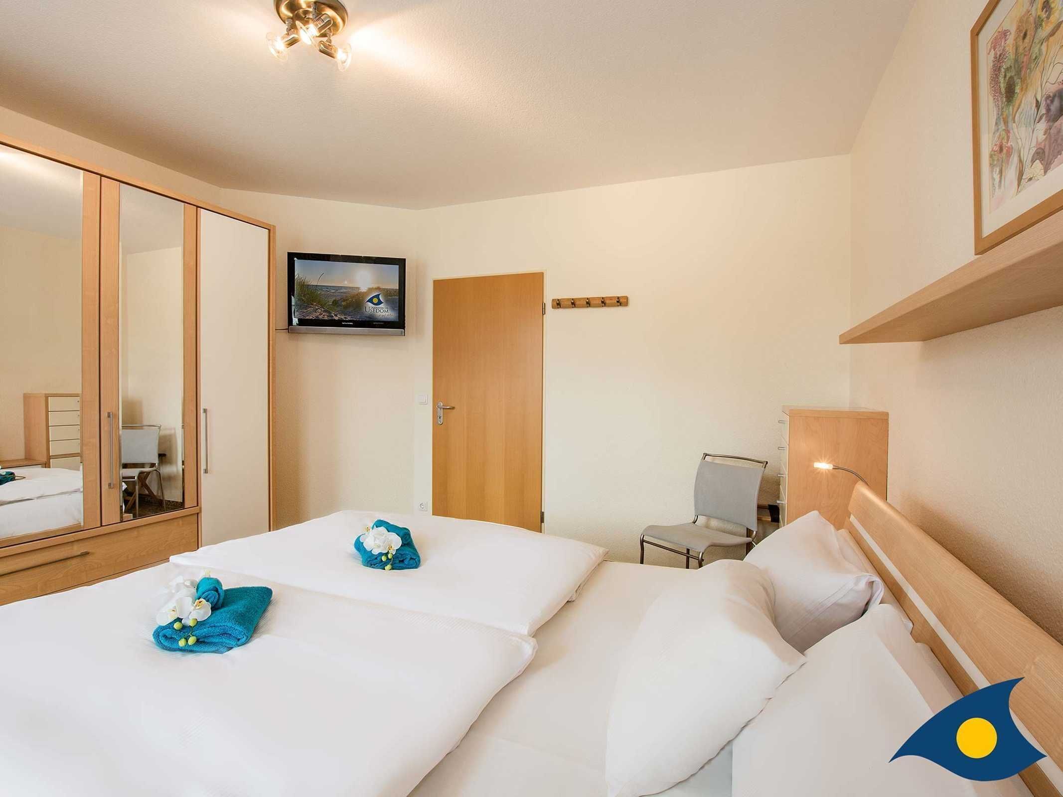 Une chambre d’hôtel avec deux lits, un grand miroir, une télévision et un petit bureau.
