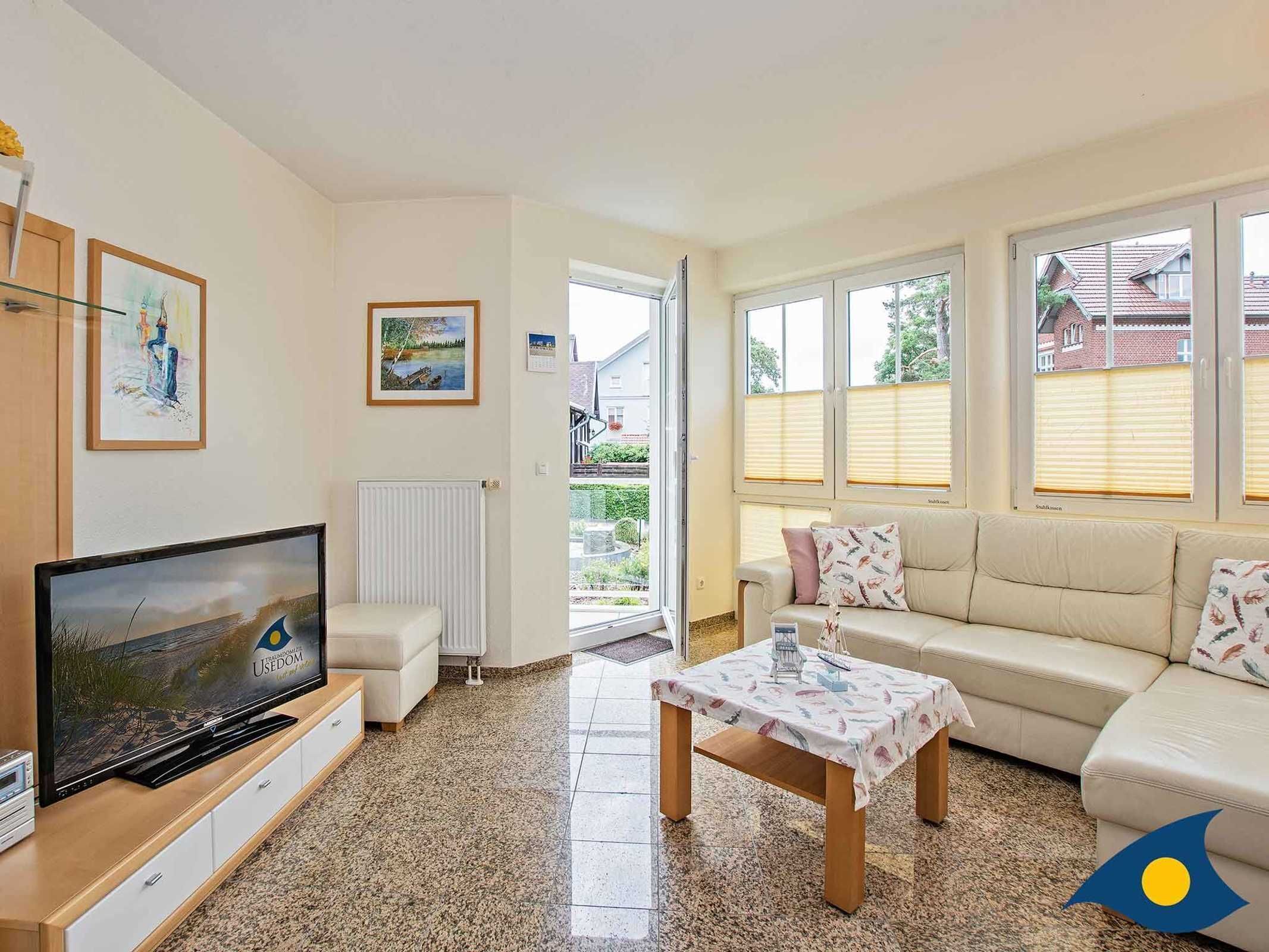 A living room with a television, sofa, coffee table, and artwork on the walls.