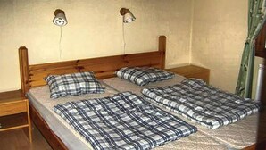 Una cama doble con cabecera de madera, dos mesitas de noche y una manta de cuadros.