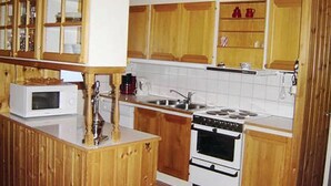 Una cocina con armarios de madera, un microondas, una estufa y un lavamanos.