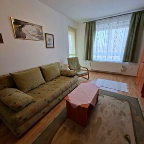 Un salon avec un canapé, un fauteuil, une petite table et un radiateur.