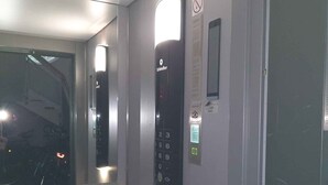 Un ascenseur moderne doté d’un panneau de commande numérique, d’une fenêtre et d’un panneau indiquant qu’il est interdit de fumer.