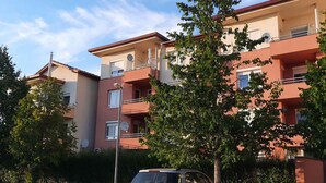 Un immeuble résidentiel à plusieurs étages, doté de balcons et d’antennes paraboliques.