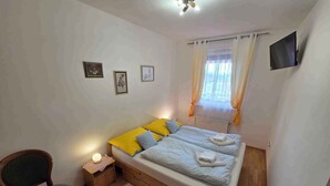 Une chambre à coucher avec un lit, une chaise, une table de chevet et une fenêtre avec des rideaux.