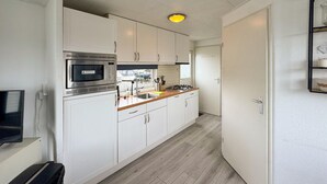 Una cucina compatta con mobili bianchi, un forno a microonde, un lavello e un piano cottura.