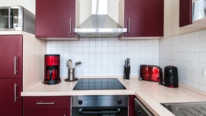 Eine Küche mit roten Schränken, einer Mikrowelle, einer Kaffeemaschine, einem Toaster und einem Herd.