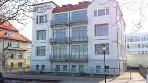 Ein mehrstöckiges Gebäude mit Balkonen, einem Schild mit der Aufschrift 'Grandhaus Mühle' und einem befestigten Eingang.