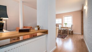 Uma cozinha moderna com bancada de madeira, radiador embutido e área de jantar com mesa e cadeiras.