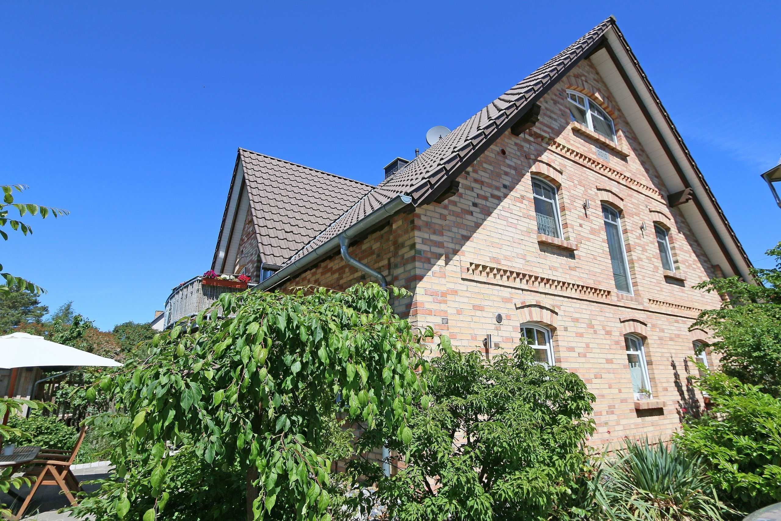 Ein großes Backsteingebäude mit einem steilen Satteldach und zahlreichen Fenstern.