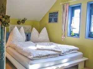 A bedroom with a bed, pillows, a window, and a painting on the wall. - Villa Ilsebill - artists' house (Ribnitz-Damgarten)