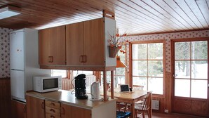 A kitchen with wooden cabinets, a microwave, a coffee maker, and a dining area with a table and chairs. - Pet friendly home in Oviken with sauna (Oviken)