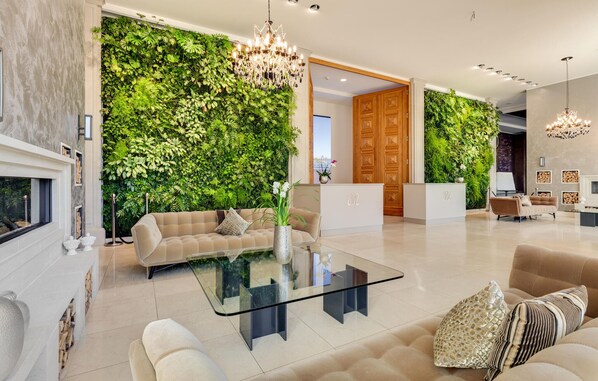 A modern living room with a glass coffee table, beige sofas, a fireplace, and a green wall with plants. - Awesome apartment in Binz with WiFi (Prora/Rügen)