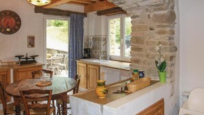 Une cuisine rustique avec des murs en pierre, des meubles en bois et une vue sur l’extérieur.