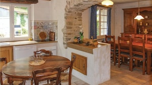 Une cuisine rustique avec une arche en pierre, des meubles en bois et un coin repas comprenant une table ronde et des chaises.
