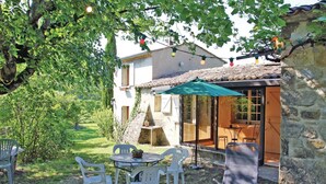 Un espace extérieur aménagé avec une table et des chaises, un mur en pierre et un bâtiment doté d’un toit en tuiles.