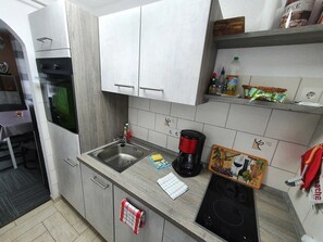 A kitchen with a sink, stove, and a coffee maker.