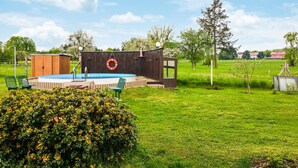 A backyard with a swimming pool, a wooden deck, and a small shed.