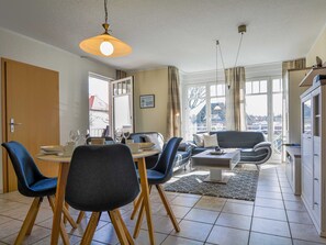 Un coin repas avec une table dressée pour deux personnes, un canapé et une table basse.