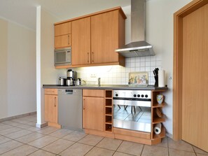 A compact kitchen with wooden cabinets, a built-in microwave, a dishwasher, and a stainless steel stove.