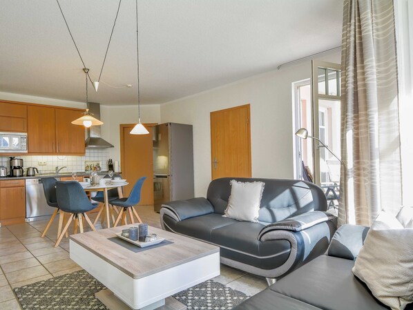A modern living room with a sofa, coffee table, and dining area.