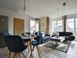 Un salon moderne avec un coin repas, comprenant un canapé, des fauteuils, une table basse et une table à manger pour quatre personnes.