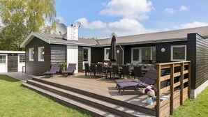 A modern outdoor deck with multiple lounge chairs and a barbecue area. - Awesome home in Væggerløse with sauna (Væggerløse)
