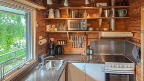 Une cuisine avec des murs en bois, un évier en acier inoxydable, un four à micro-ondes, une cuisinière et divers ustensiles et appareils de cuisine.
