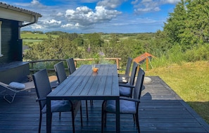 Eine Terrasse mit Tisch und Stühlen, mit Blick auf eine reizvolle Landschaft.