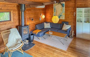 A cozy cabin interior with a wood-burning stove, a sofa, a dining table, and a map on the wall.