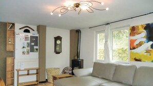 A living room with a sofa, a wooden cabinet, a wall clock, and a window with a view of greenery. - Gorgeous home in Vianden with WiFi (Vianden)
