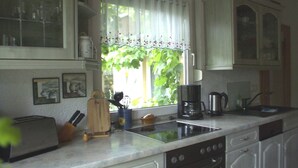 A kitchen with a window, a coffee maker, a toaster, and cabinets. - Flower House - Flower House * (Rankwitz)