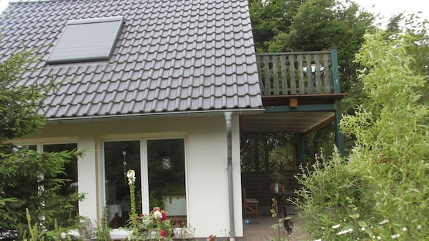 A house with a tiled roof, a balcony with a railing, and a garden with various plants and flowers. - Flower House - Flower House * (Rankwitz)