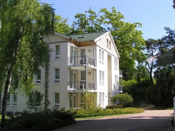 A multi-story residential building with balconies, surrounded by greenery.